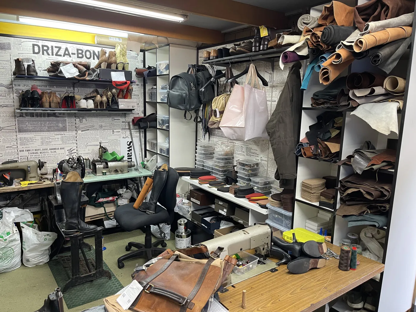 Inside the Highlands Cobbler workshop: rolls of leather hides on tall shelves above the bench